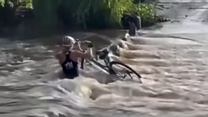 A female cyclist survived miraculously after being sucked underwater while trying to cross a flooded